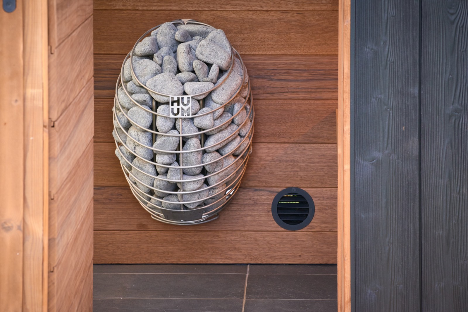 Interieur van een SKLP-S42 buitensauna met HUUM-saunakachel tegen een thermowood-wand